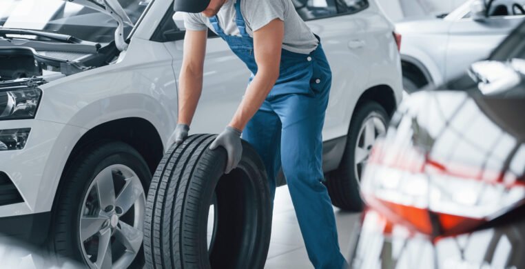 Need to hurry. Mechanic holding a tire at the repair garage. Replacement of winter and summer tires Need to hurry. Mechanic holding a tire at the repair garage. Replacement of winter and summer tires.